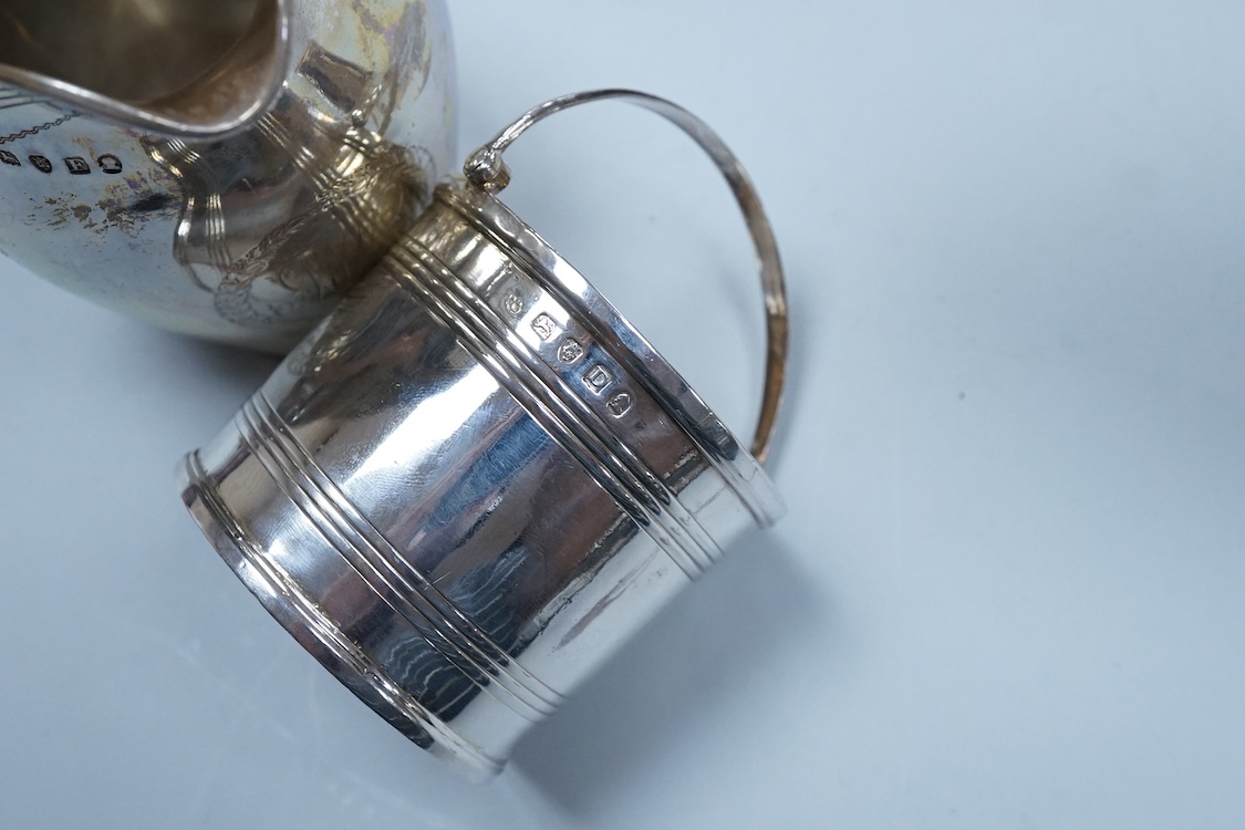A George III silver cream jug, of oval form, London, 1801, 11cm, a George III silver helmet shaped cream jug, London, 1793, a George III small silver sugar pail, London, 1799 and a George V silver 'whisky' label, 8.4oz.